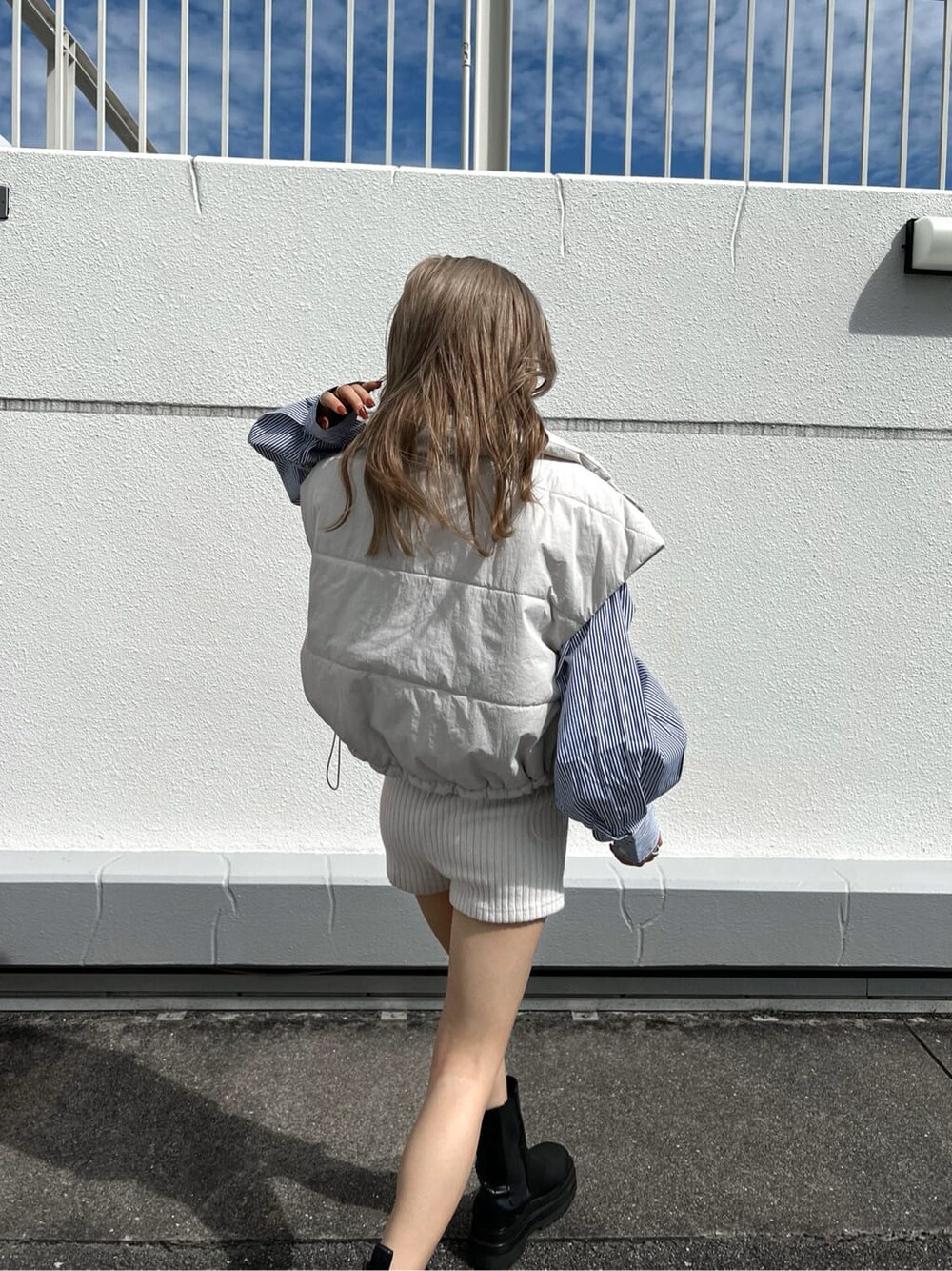 ブルー系のシャツ/ブラウス、ホワイト系のダウンベストを着用したレディースの秋コーディネートの1枚目の写真