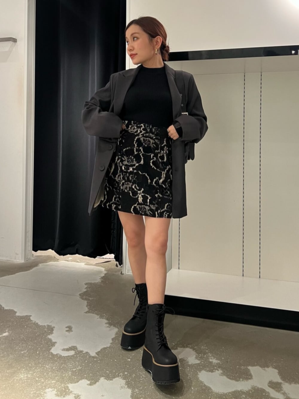 ブラック系のハンドバッグ、ブラウン系のブーツ、ブラック系のニット/セーターを着用したレディースの秋コーディネートの1枚目の写真