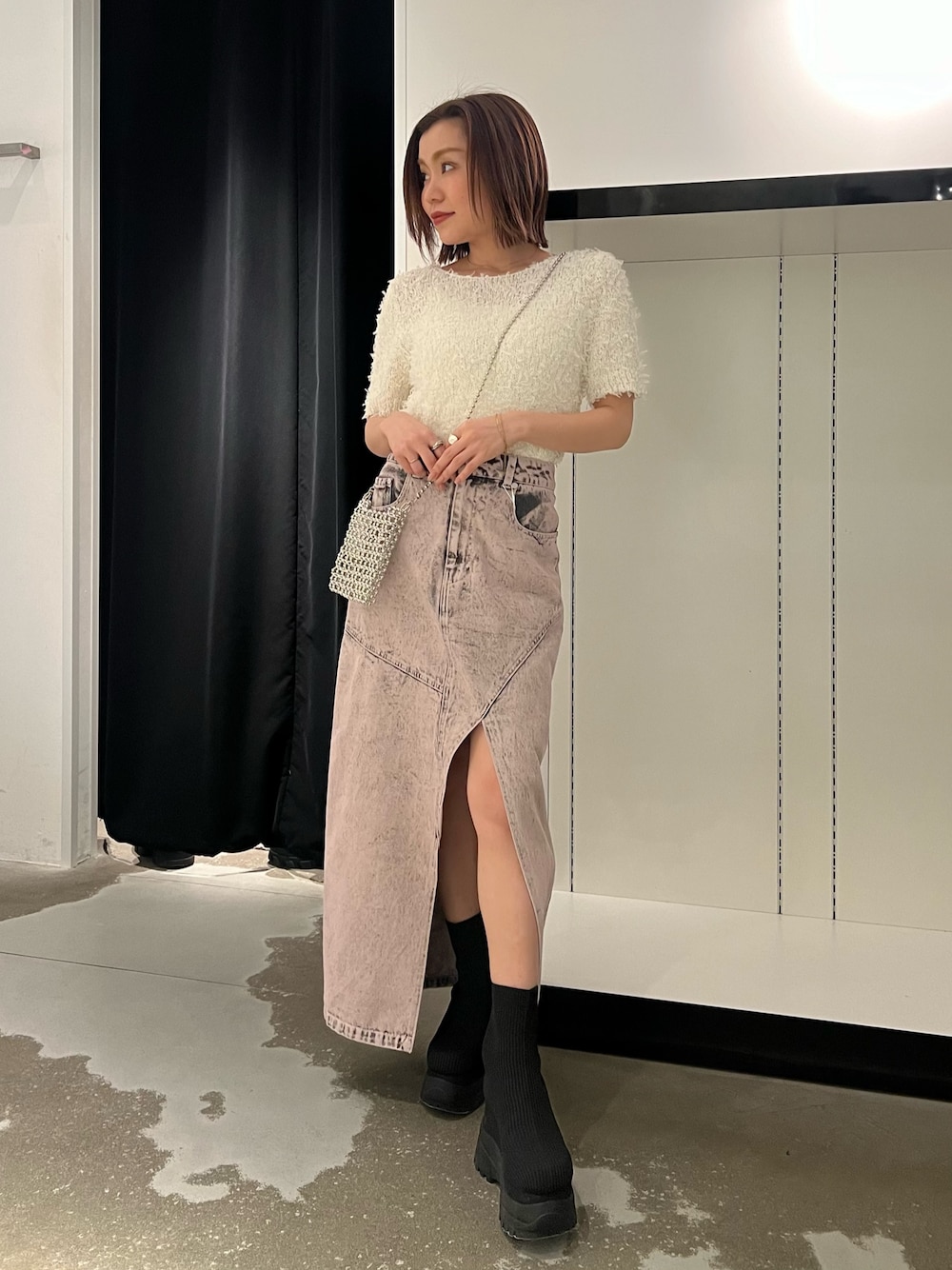 ホワイト系のニット/セーター、ピンク系のデニムスカート、ブラック系のブーツを着用したレディースの春コーディネートの1枚目の写真