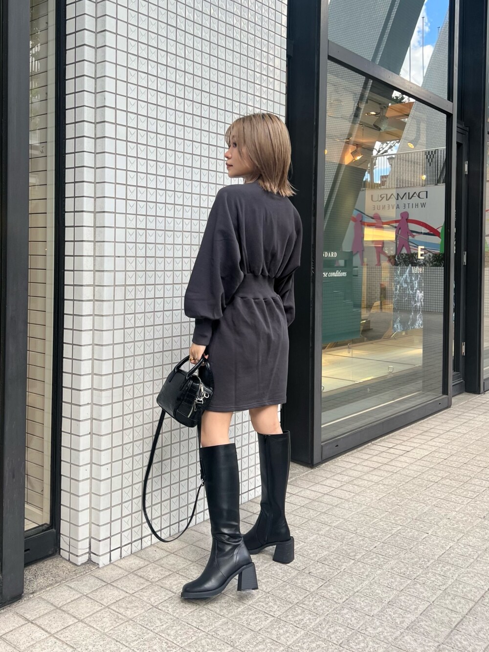 グレー系のワンピース、ブラック系のブーツ、ブラック系のボストンバッグを着用したレディースの夏コーディネートの1枚目の写真