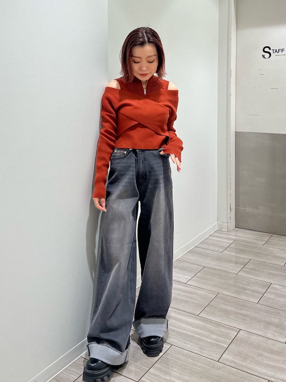 オレンジ系のニット/セーター、グレー系のデニムパンツを着用したレディースの冬コーディネートの1枚目の写真