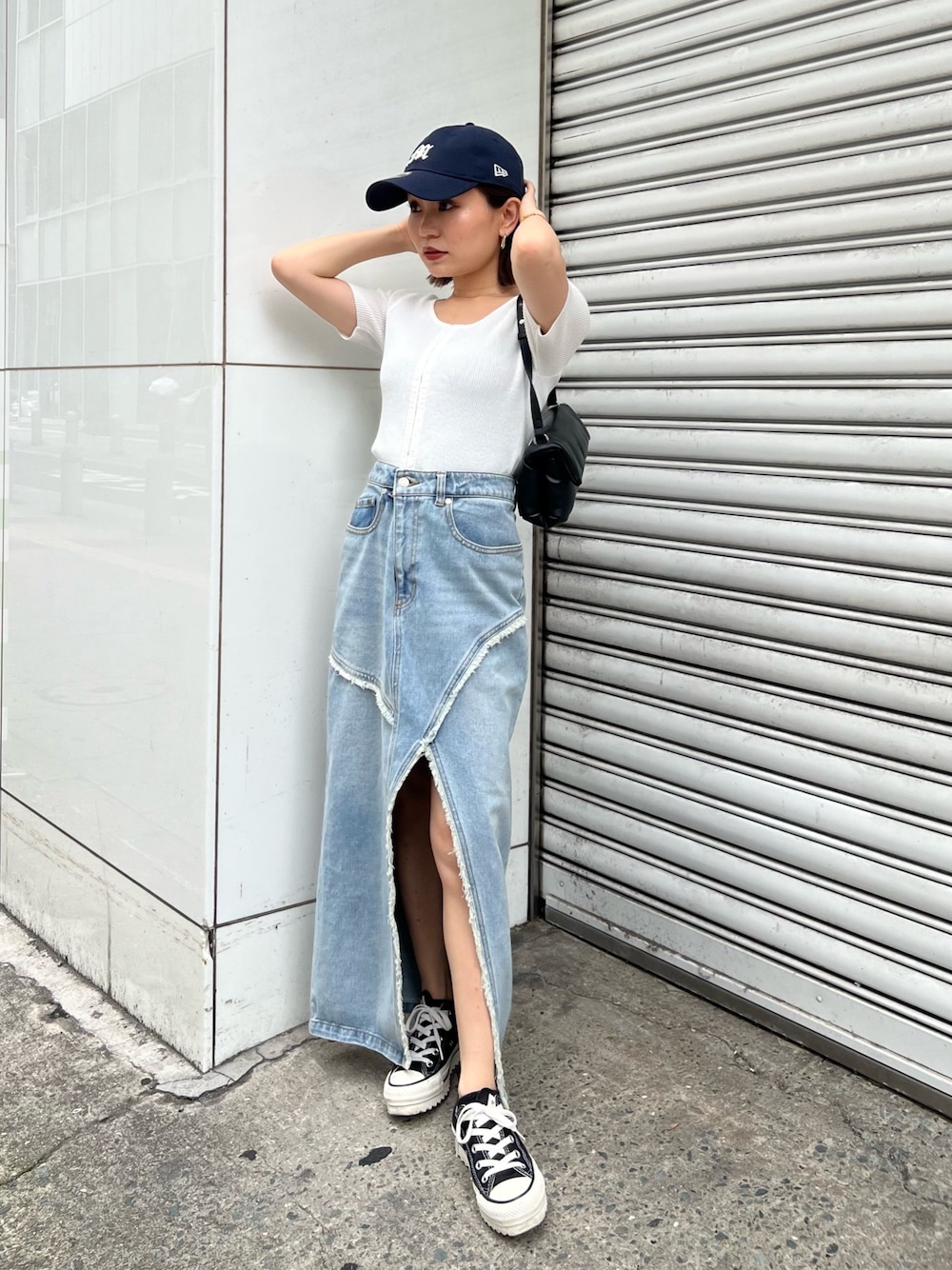 ホワイト系のニット/セーター、ブルー系のデニムスカート、ブラック系のハンドバッグを着用したレディースの夏コーディネートの1枚目の写真