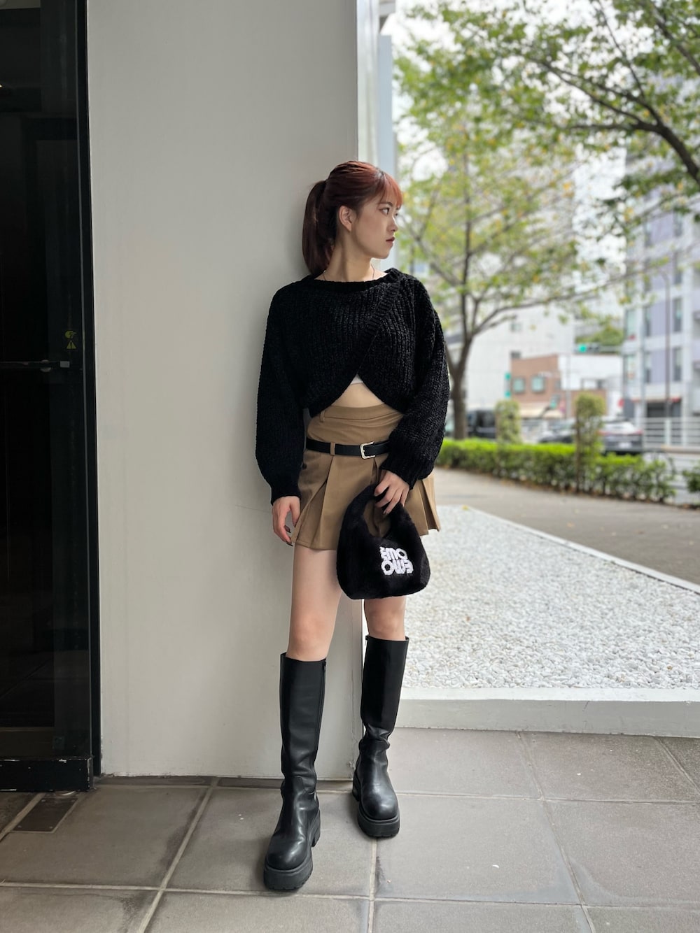 ブラック系のハンドバッグ、ブラック系のニット/セーター、ベージュ系のスカートを着用したレディースの秋コーディネートの1枚目の写真