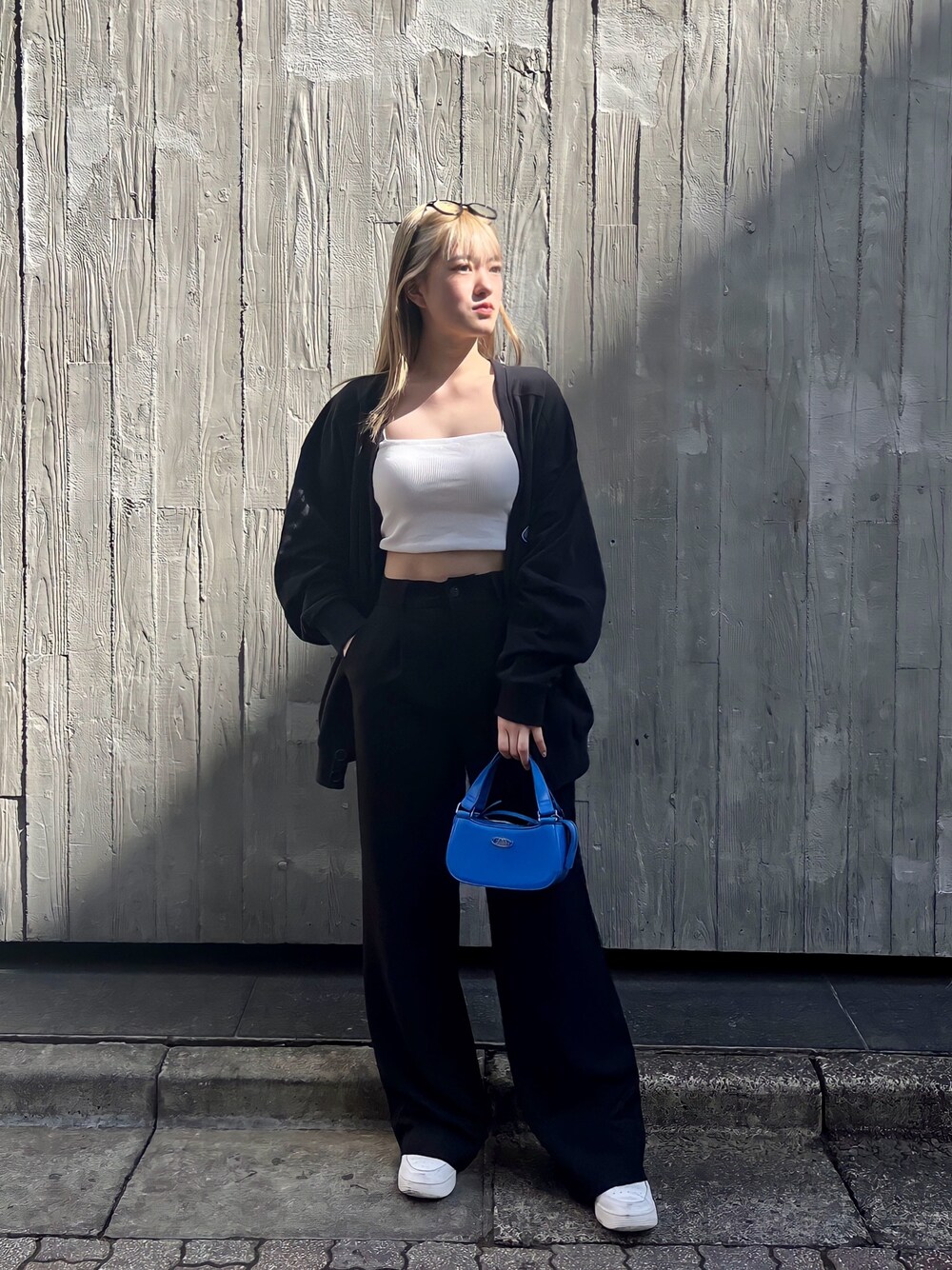 ホワイト系のキャミソール、ブラック系のカーディガン/ボレロ、ブルー系のハンドバッグを着用したレディースの春コーディネートの1枚目の写真