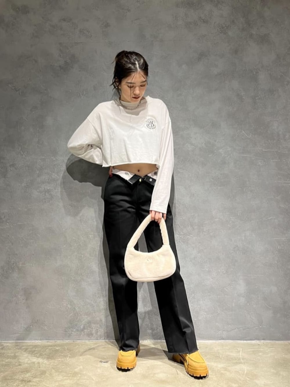 ホワイト系のハンドバッグ、ホワイト系のTシャツ/カットソー、ブラウン系のブーツを着用したレディースの秋コーディネートの1枚目の写真