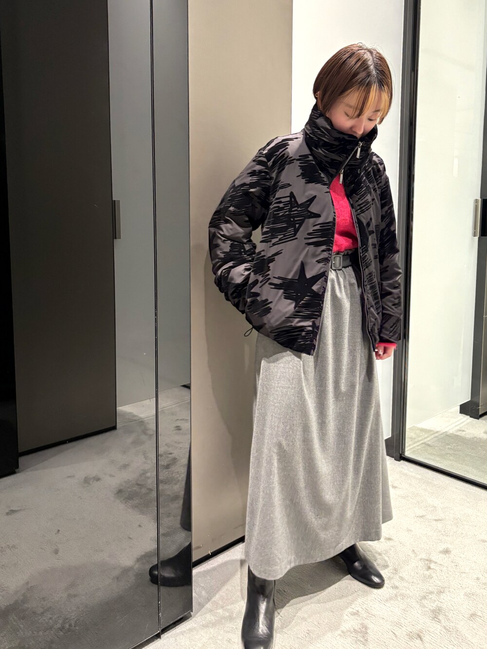 ブラック系のダウンジャケット/コート、レッド系のニット/セーター、グレー系のスカートを着用したレディースの秋コーディネートの1枚目の写真