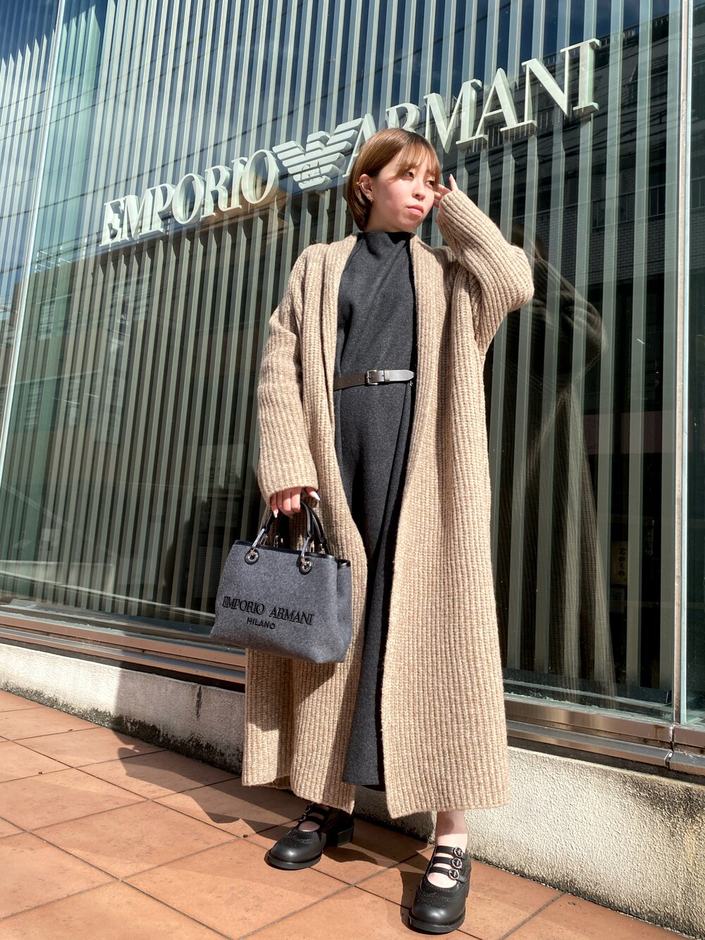 グレー系のワンピース、ベージュ系のカーディガン/ボレロ、グレー系のショルダーバッグを着用したレディースの秋コーディネートの1枚目の写真