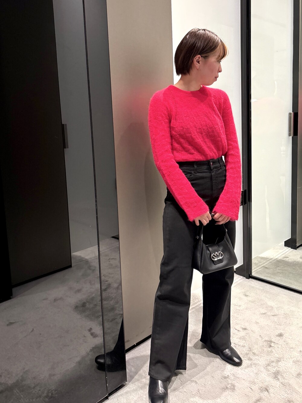 レッド系のニット/セーター、ブラック系のデニムパンツ、ブラック系のハンドバッグを着用したレディースの秋コーディネートの1枚目の写真