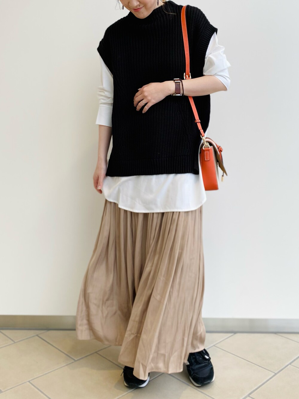 ブラック系のニット/セーター、ベージュ系のスカート、オレンジ系のショルダーバッグを着用したレディースの春コーディネートの1枚目の写真