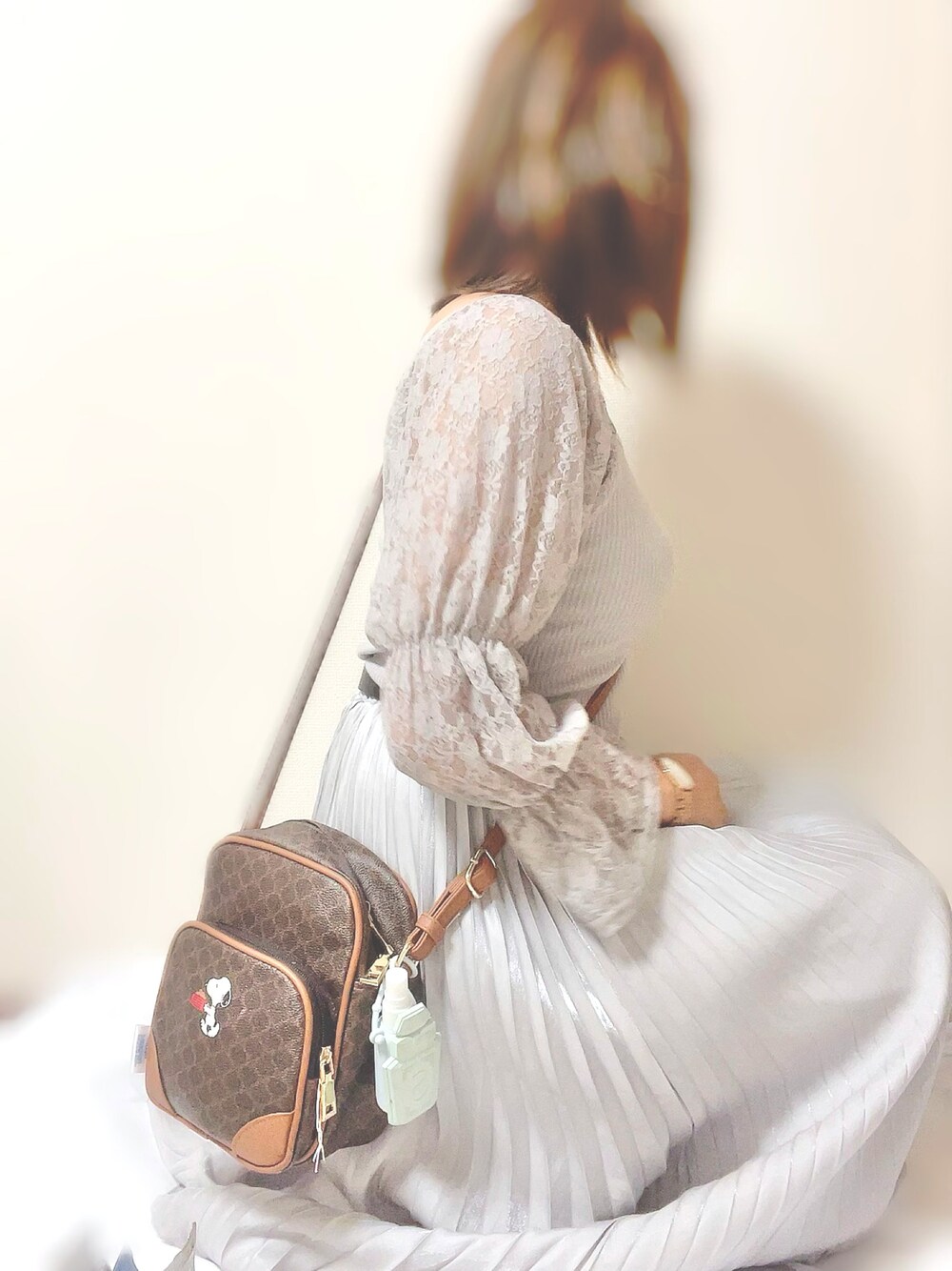 グレー系のトップス、グレー系のスカート、ブラウン系のバッグを着用したレディースの秋コーディネートの1枚目の写真