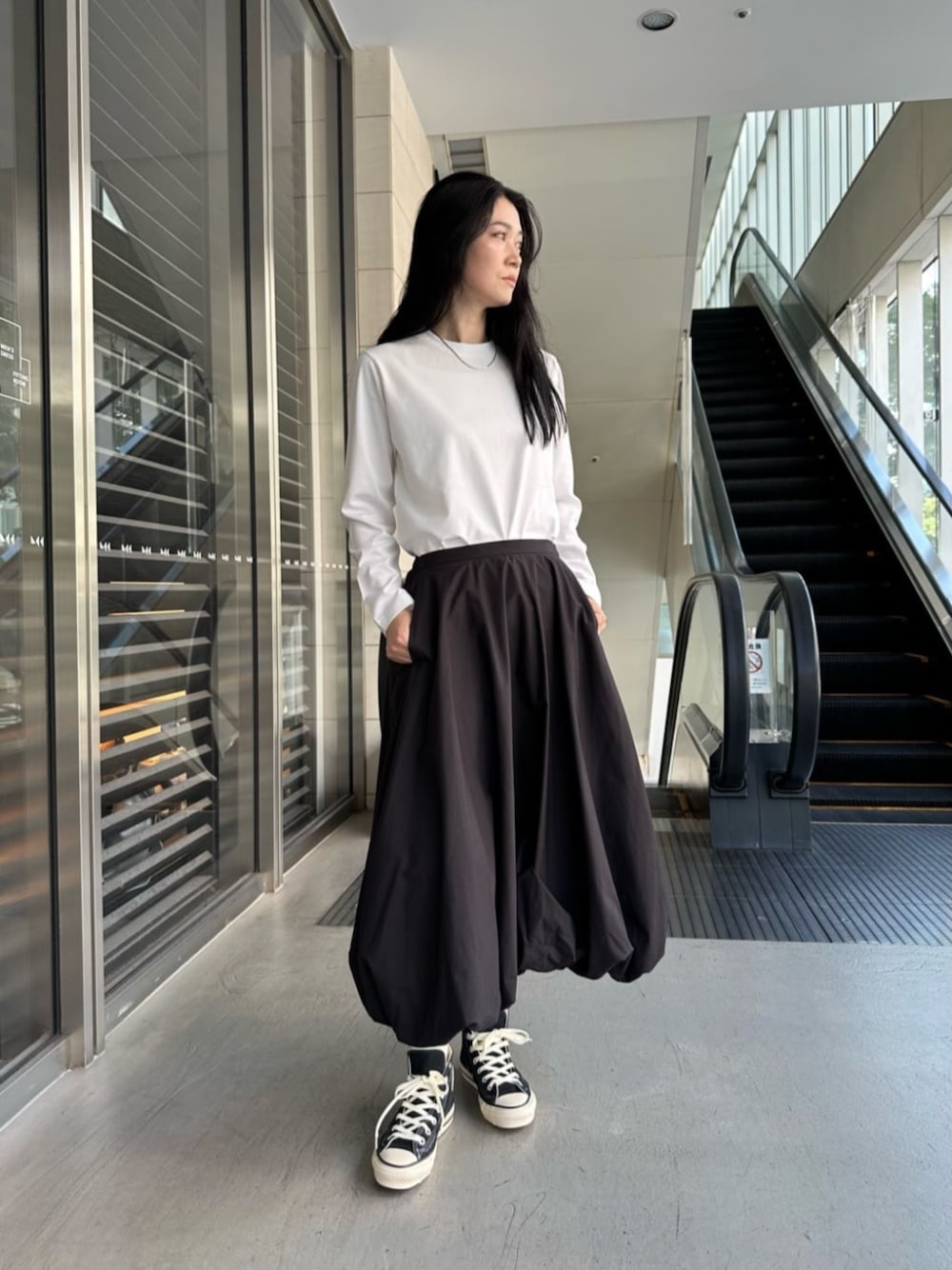 ブラック系のスカート、ブルー系のスニーカーを着用したレディースの夏コーディネートの1枚目の写真