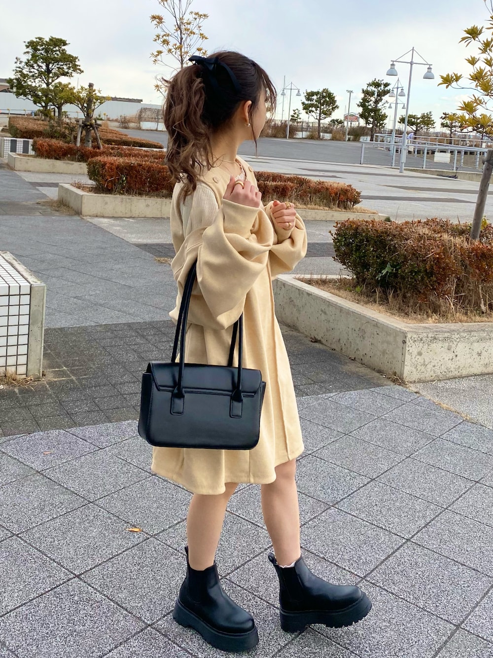 ブラック系のハンドバッグ、ホワイト系のTシャツ/カットソー、ホワイト系のカーディガン/ボレロを着用したレディースの冬コーディネートの1枚目の写真