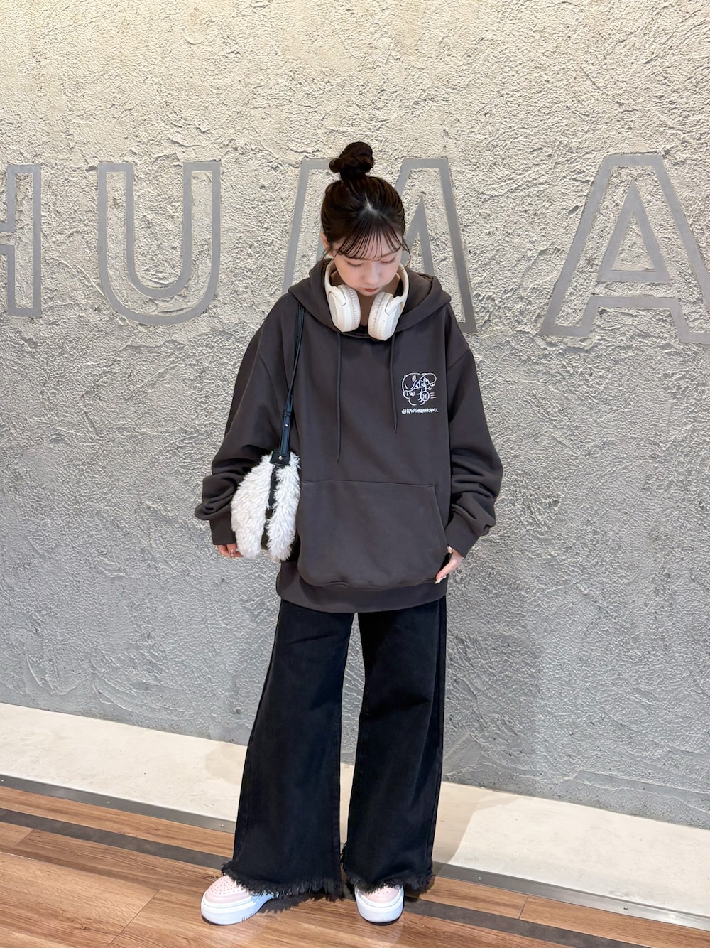 ブラック系のデニムパンツ、ホワイト系のショルダーバッグ、ピンク系のスニーカーを着用したレディースの秋コーディネートの1枚目の写真