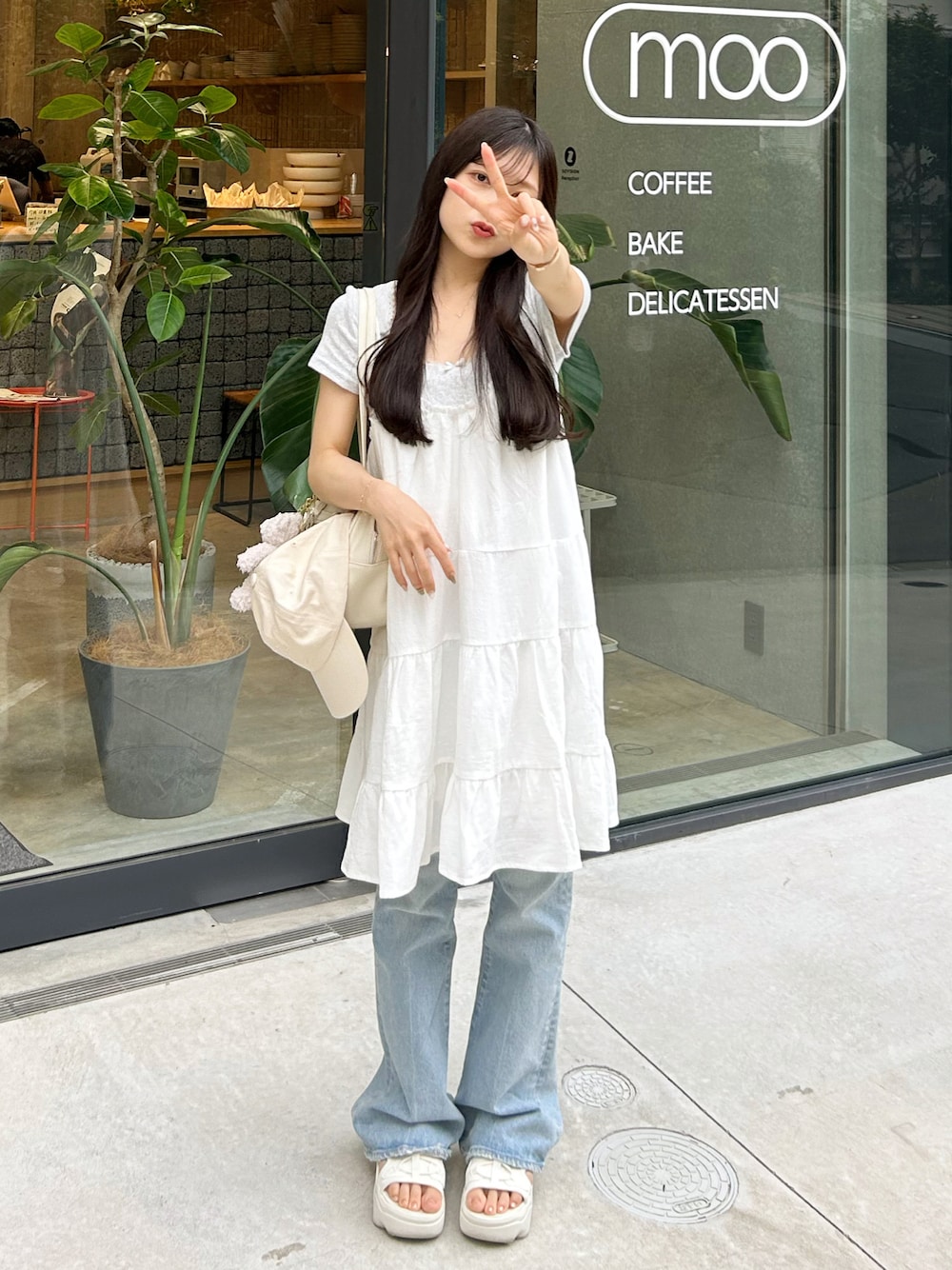 ブルー系のデニムパンツ、ホワイト系のワンピース、ホワイト系のショルダーバッグを着用したレディースの夏コーディネートの1枚目の写真