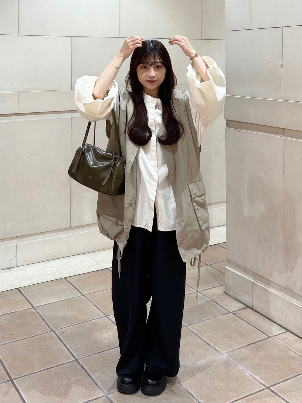 ブラック系のスラックス、ベージュ系のシャツ/ブラウス、グリーン系のトートバッグを着用したレディースの秋コーディネートの1枚目の写真