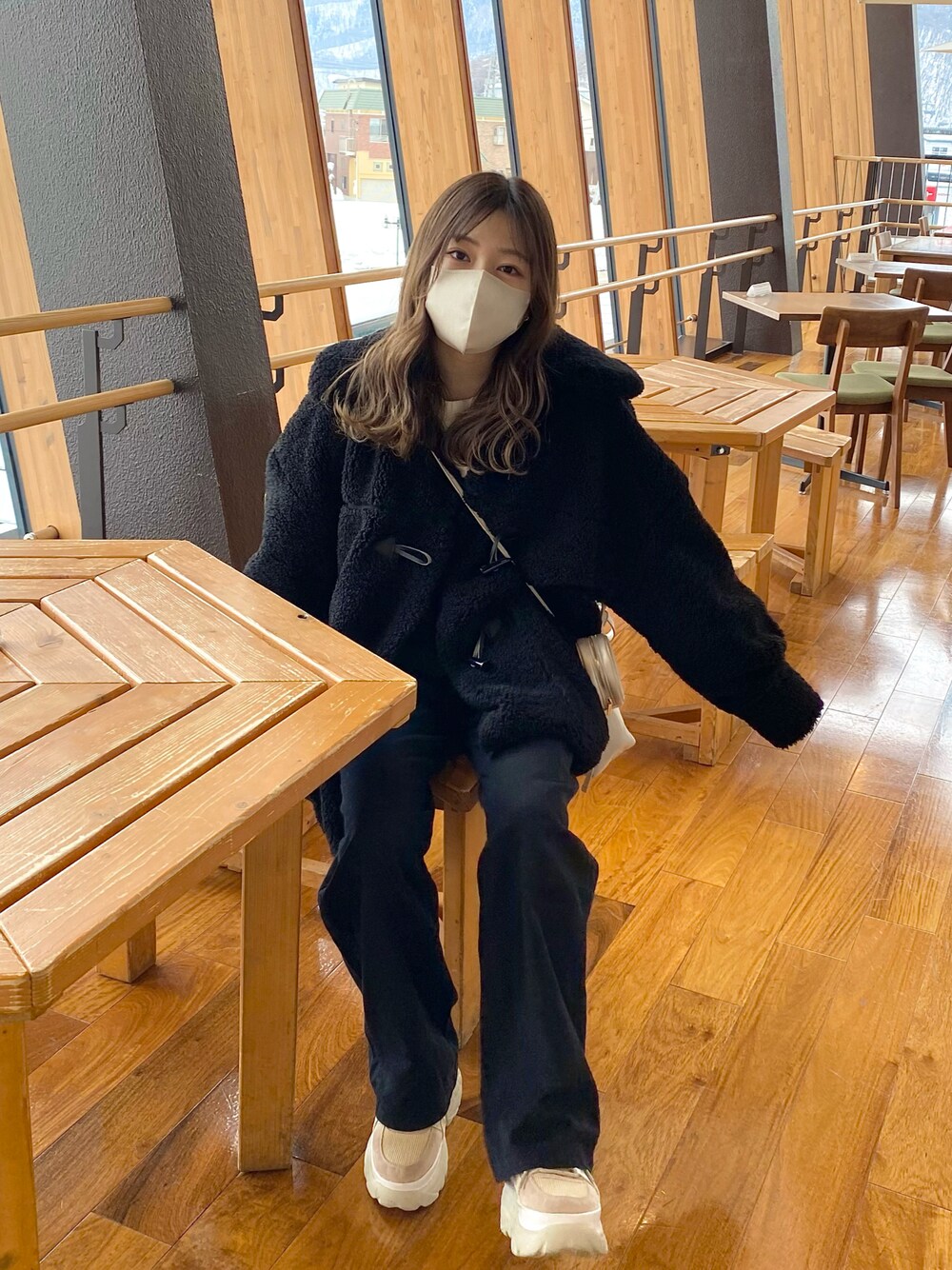 ベージュ系のスニーカー、ブラック系のダッフルコート、ホワイト系のスウェットを着用したレディースの冬コーディネートの1枚目の写真