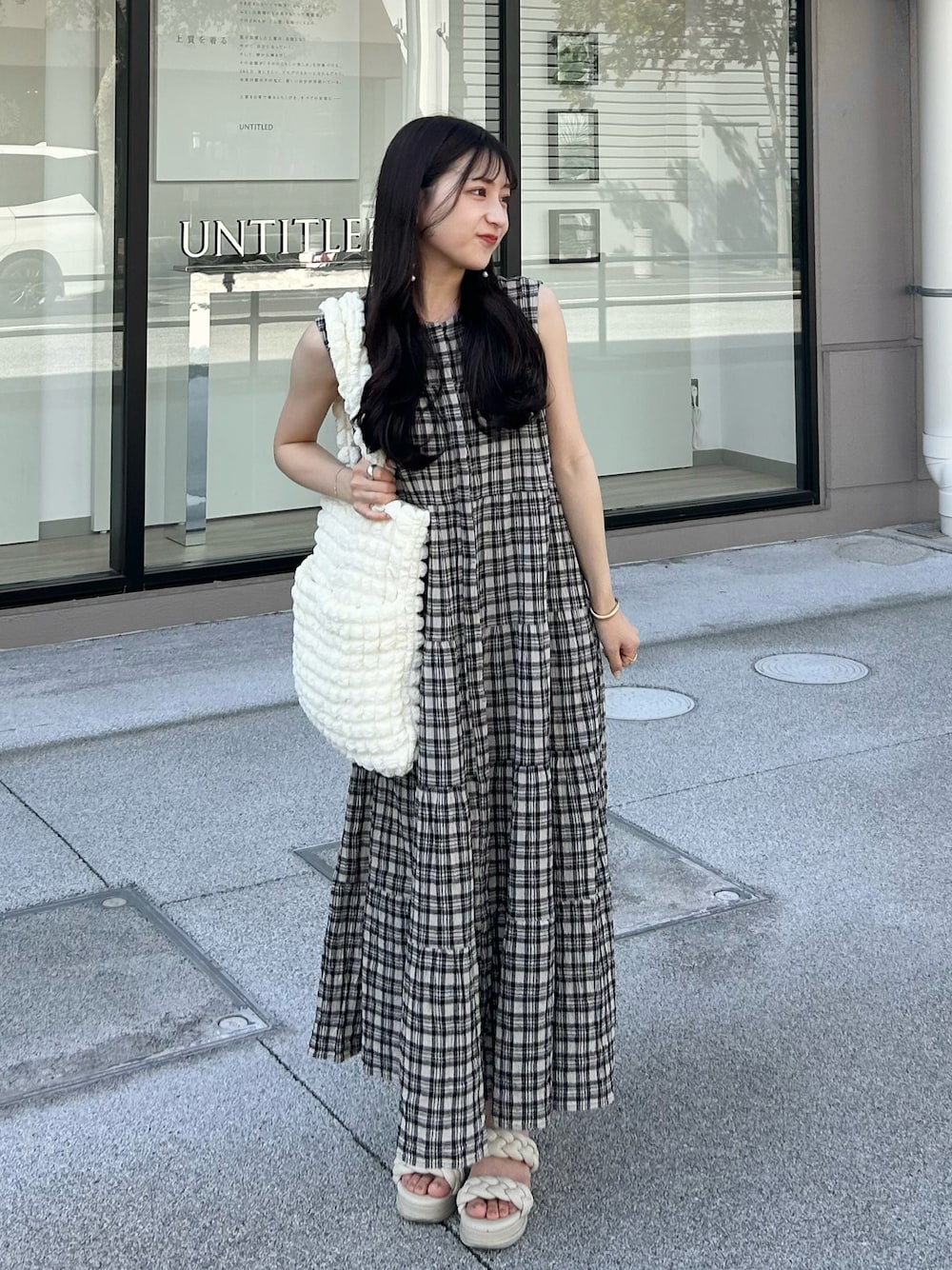 ホワイト系のサンダル、ブラック系のワンピース/ドレス、ホワイト系のトートバッグを着用したレディースの夏コーディネートの1枚目の写真