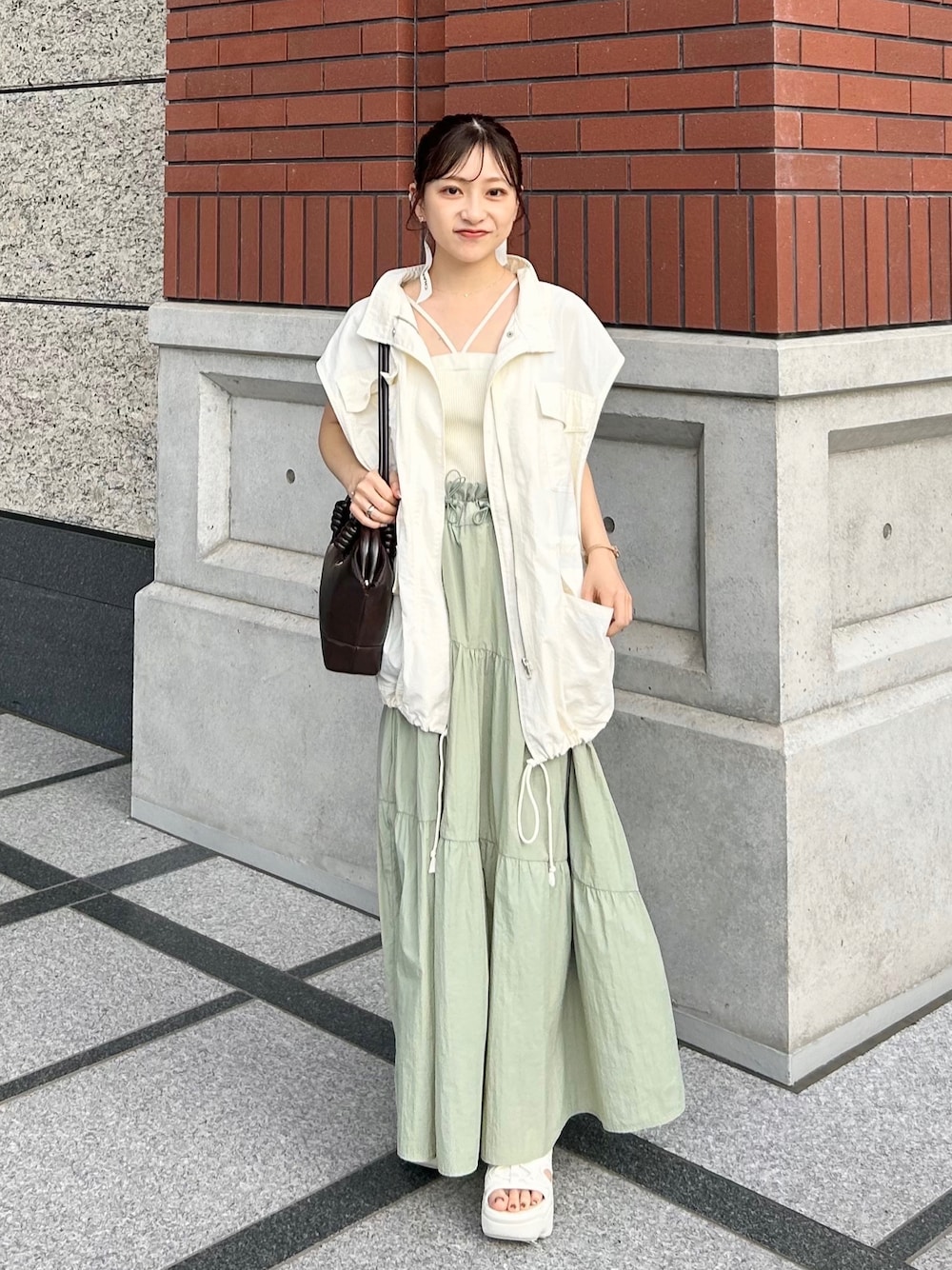 ブラウン系のショルダーバッグ、ホワイト系のミリタリージャケット、ホワイト系のキャミソールを着用したレディースの秋コーディネートの1枚目の写真