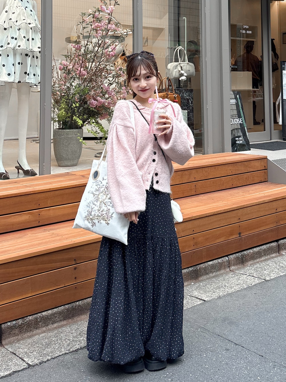 ホワイト系のスカート、ピンク系のカーディガン/ボレロ、ホワイト系のパーカーを着用したレディースの春コーディネートの1枚目の写真