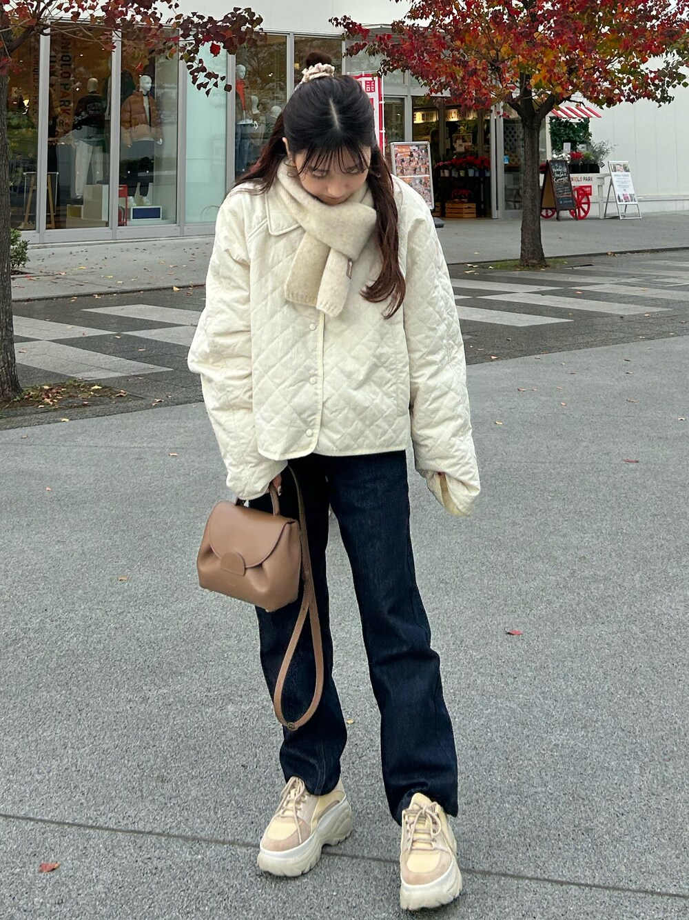 ブルー系のデニムパンツ、ブラウン系のバッグ、ホワイト系のジャケット/アウターを着用したレディースの秋コーディネートの1枚目の写真