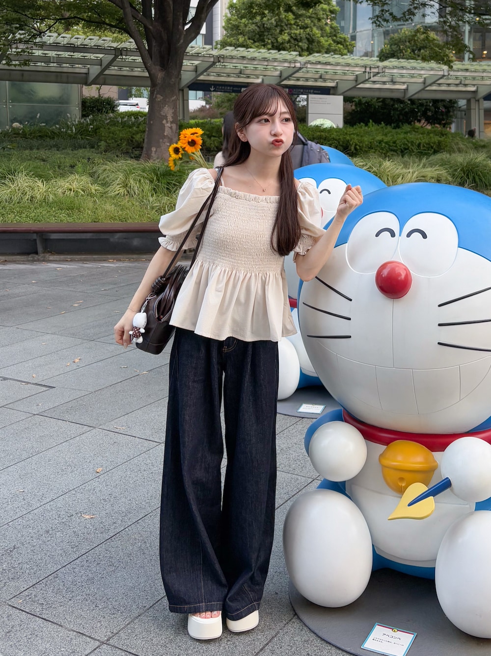 ブルー系のデニムパンツ、ホワイト系のトップス、ブラウン系のショルダーバッグを着用したレディースの夏コーディネートの1枚目の写真