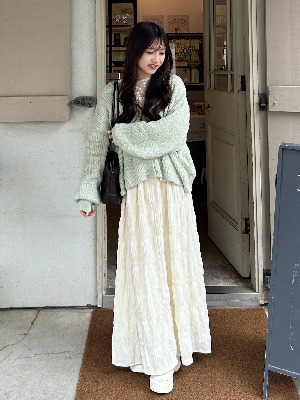 グリーン系のカーディガン/ボレロ、ベージュ系のシャツ/ブラウス、ホワイト系のワンピースを着用したレディースの春コーディネートの1枚目の写真