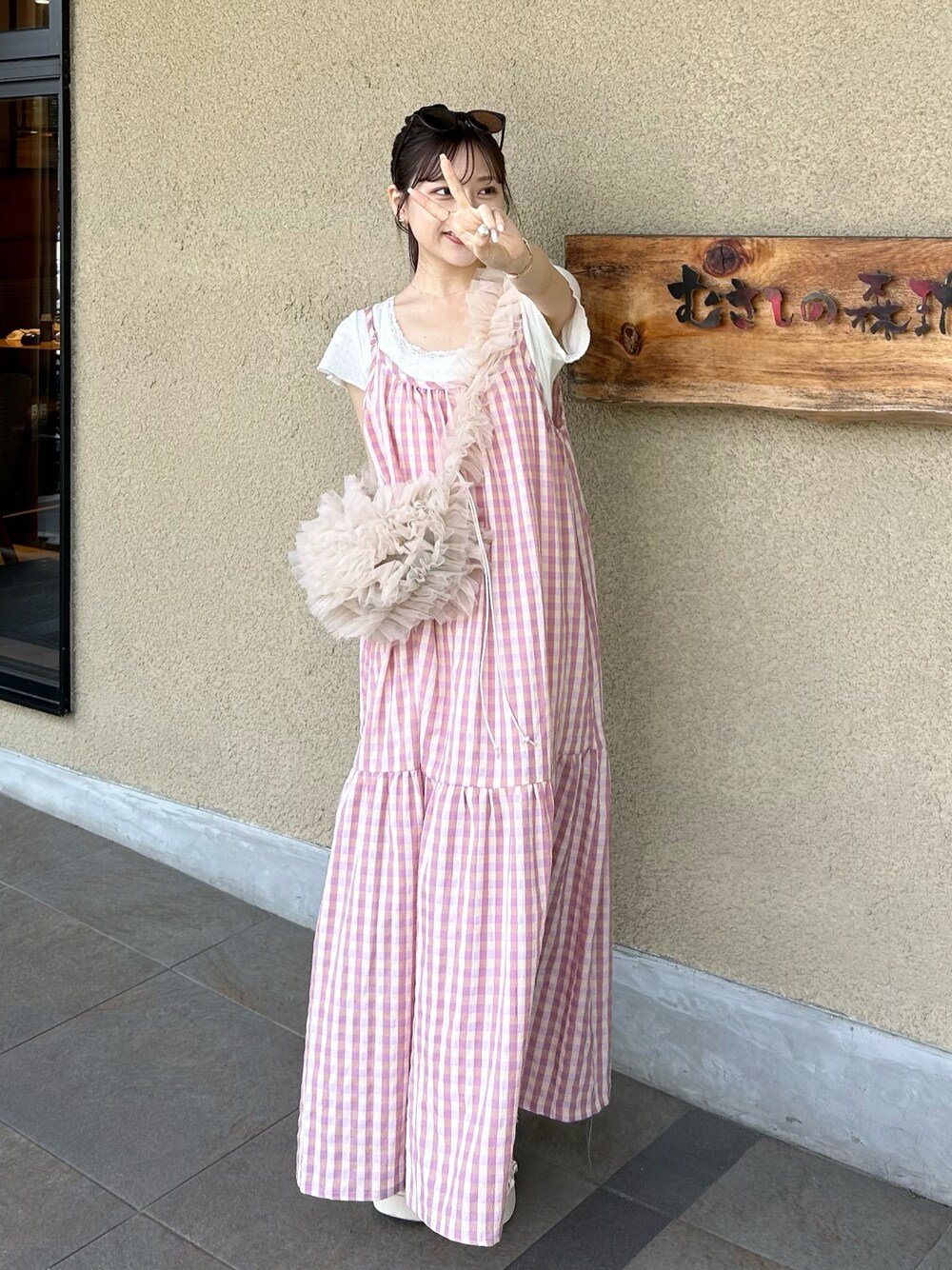 ピンク系のハンドバッグ、ホワイト系のサンダル、ホワイト系のトップスを着用したレディースの夏コーディネートの1枚目の写真