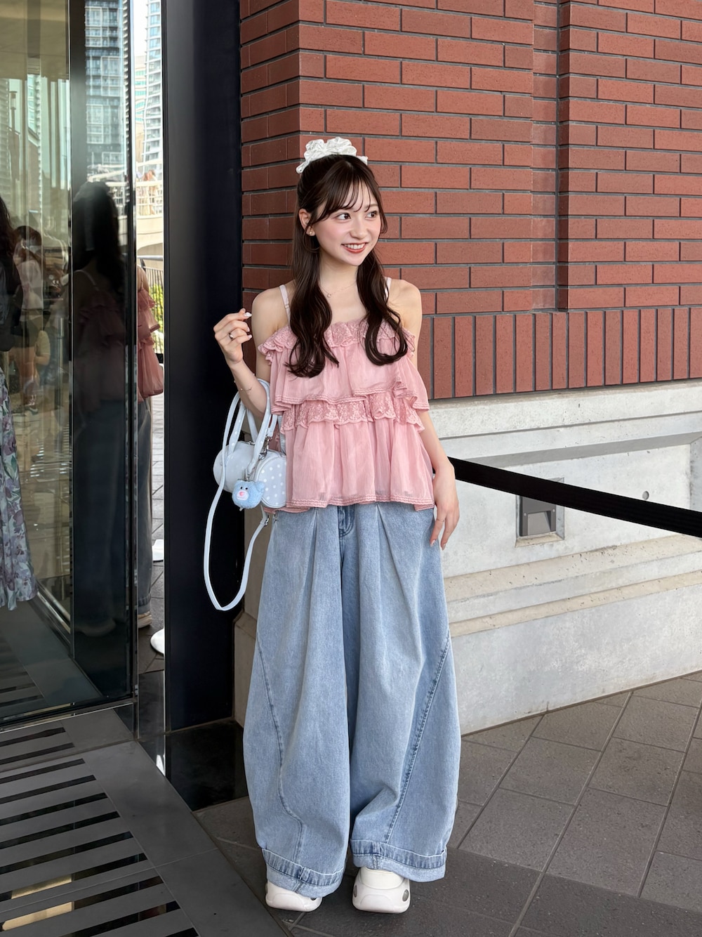 ブルー系のデニムパンツ、ホワイト系のトップス、ホワイト系のスニーカーを着用したレディースの夏コーディネートの1枚目の写真