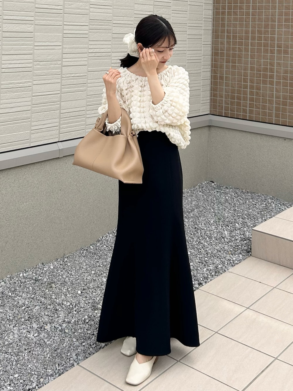 ベージュ系のバッグ、ホワイト系のTシャツ/カットソー、ブラック系のスカートを着用したレディースの春コーディネートの1枚目の写真