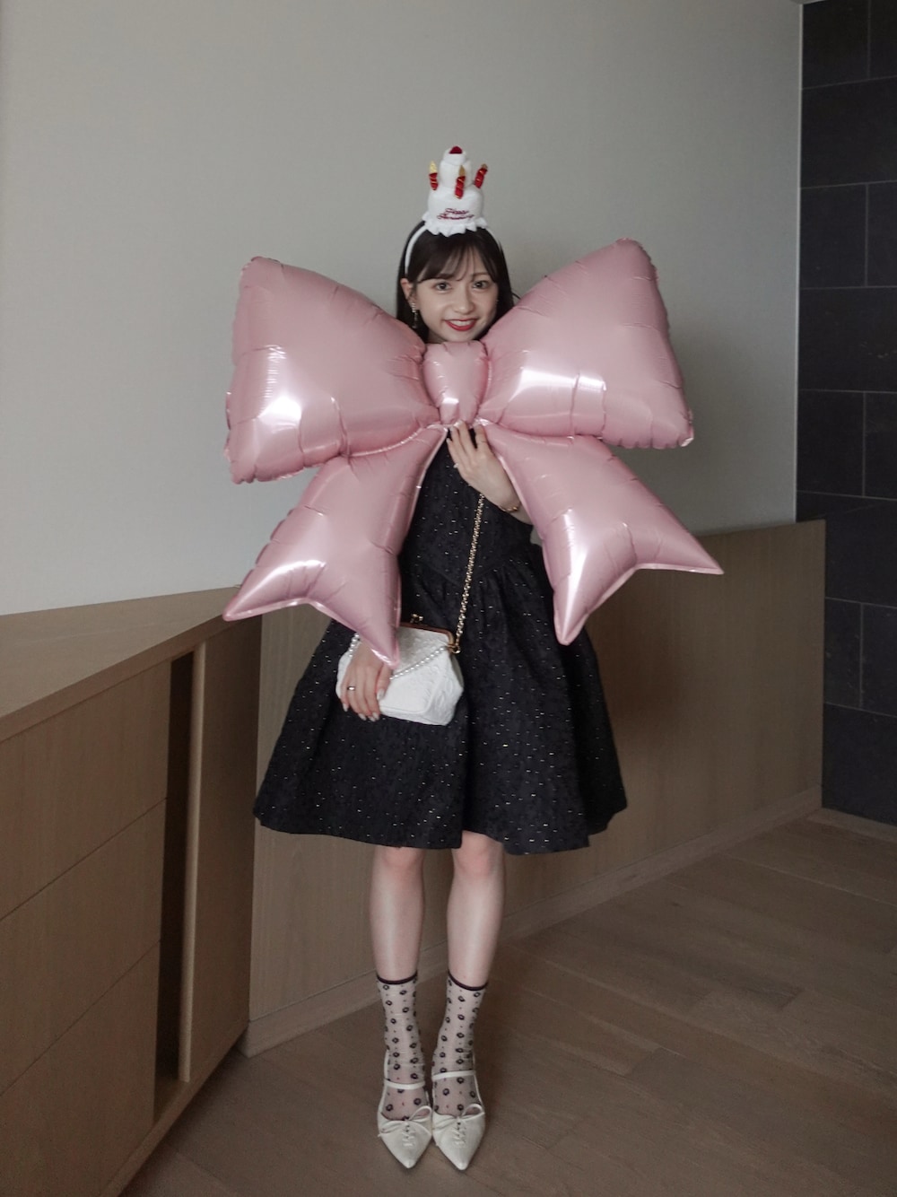 ホワイト系のパンプス、ホワイト系のハンドバッグ、ブラック系のドレスを着用したレディースの夏コーディネートの1枚目の写真