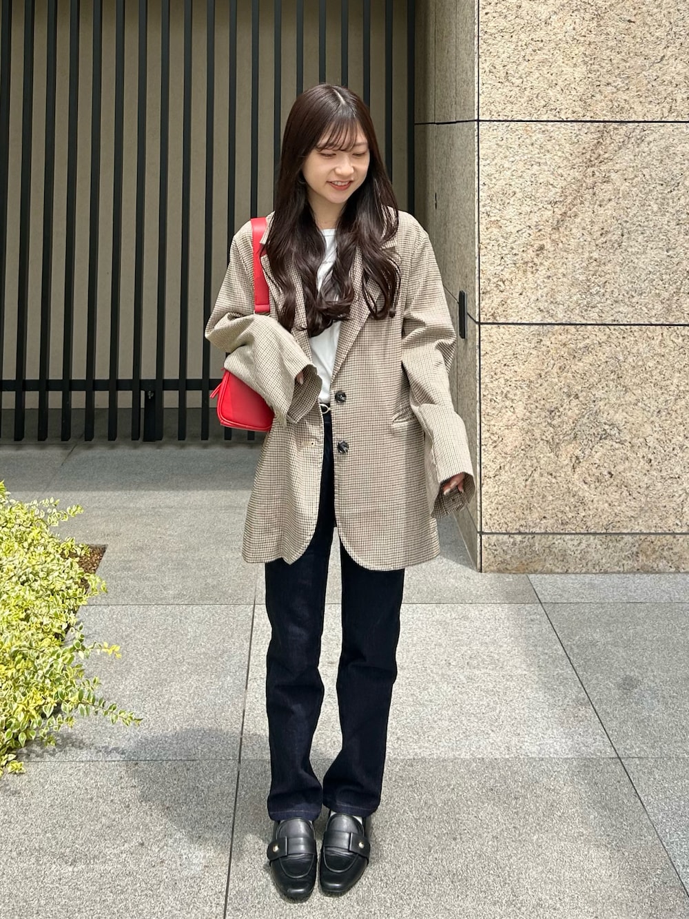 ブルー系のデニムパンツ、ベージュ系のテーラードジャケット、レッド系のショルダーバッグを着用したレディースの夏コーディネートの1枚目の写真