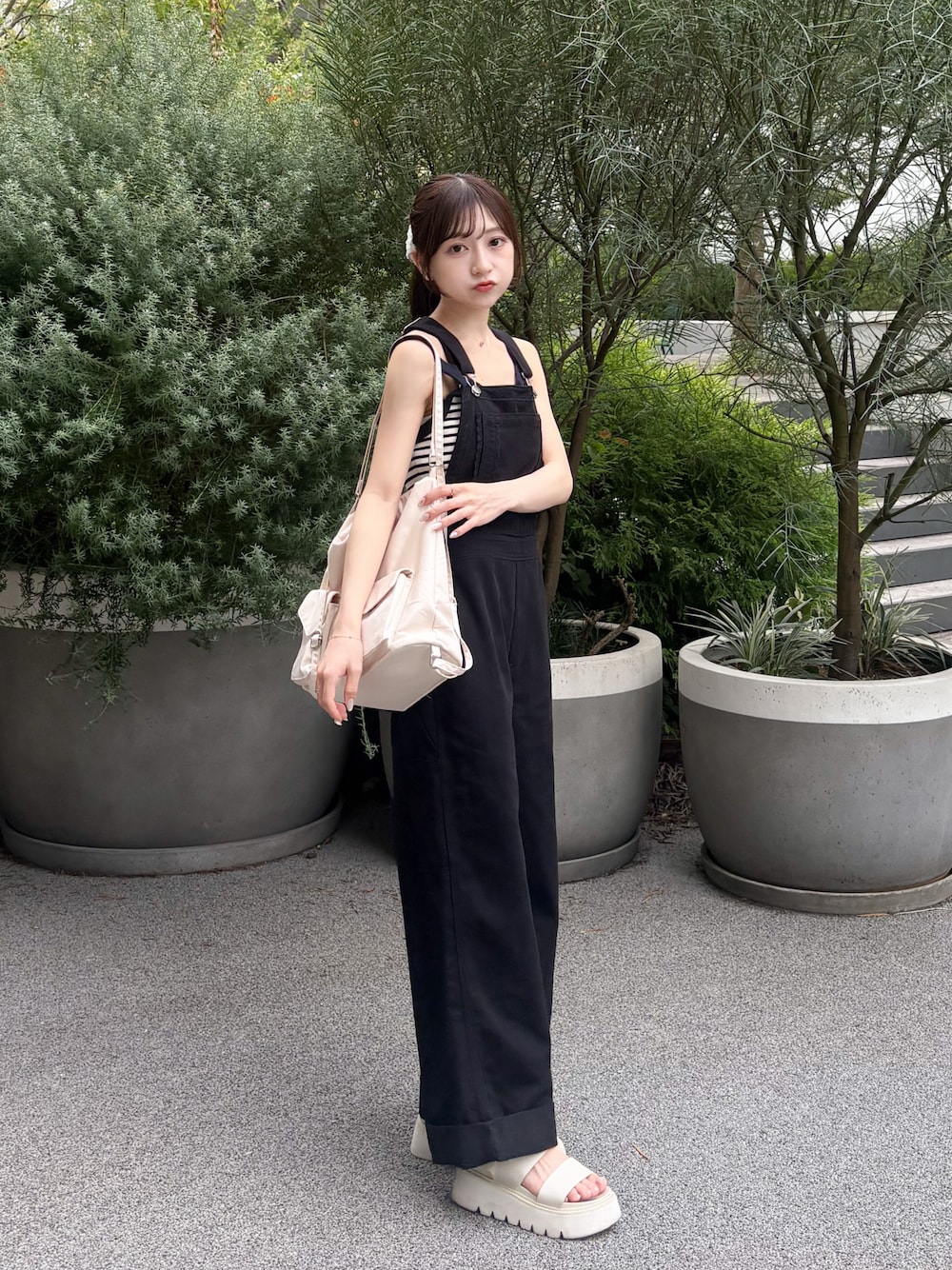 ホワイト系のトートバッグ、ブラック系のデニムパンツ、ホワイト系のサンダルを着用したレディースの夏コーディネートの1枚目の写真