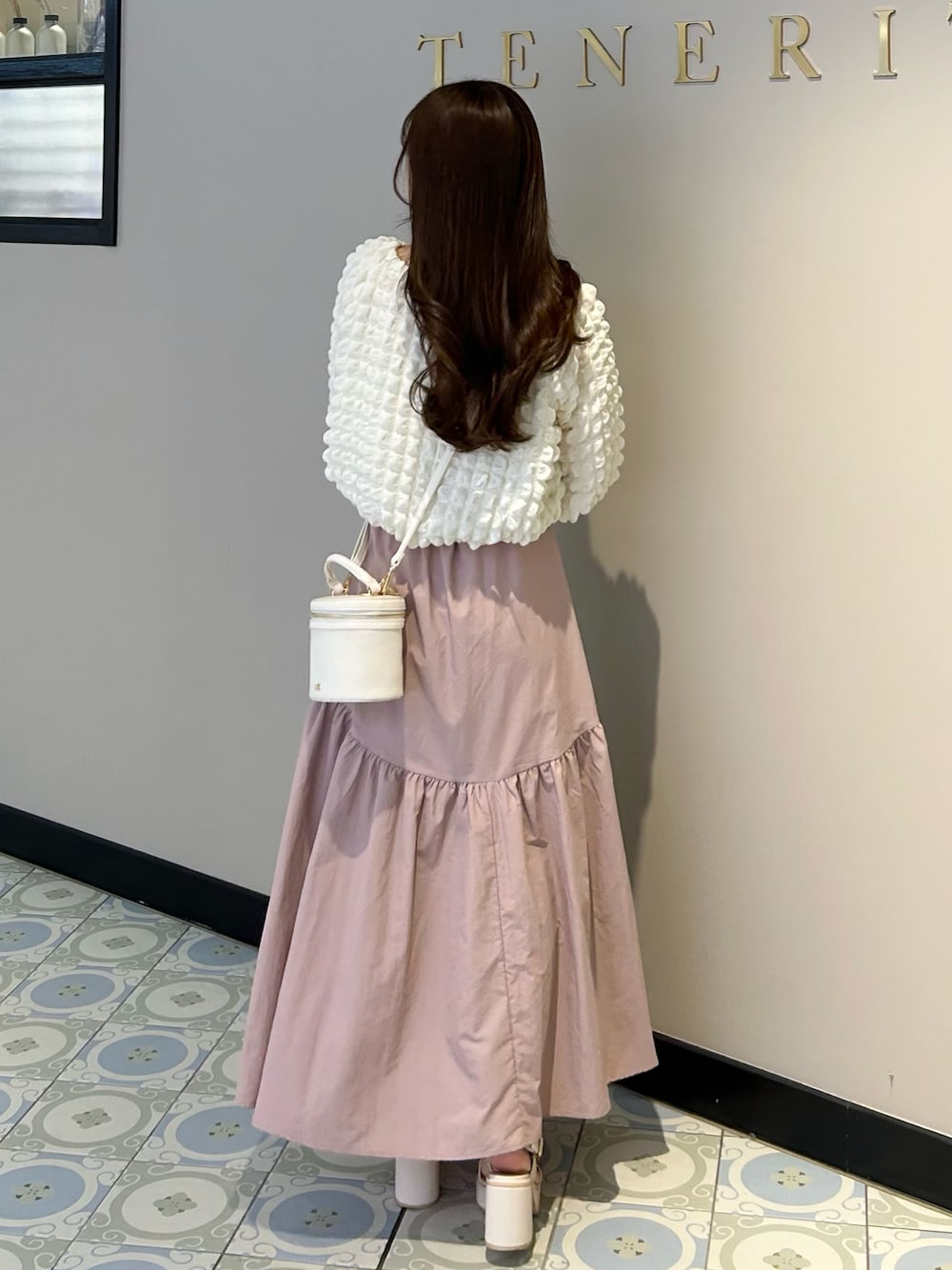 ホワイト系のショルダーバッグ、ピンク系のスカート、ホワイト系のTシャツ/カットソーを着用したレディースの春コーディネートの1枚目の写真