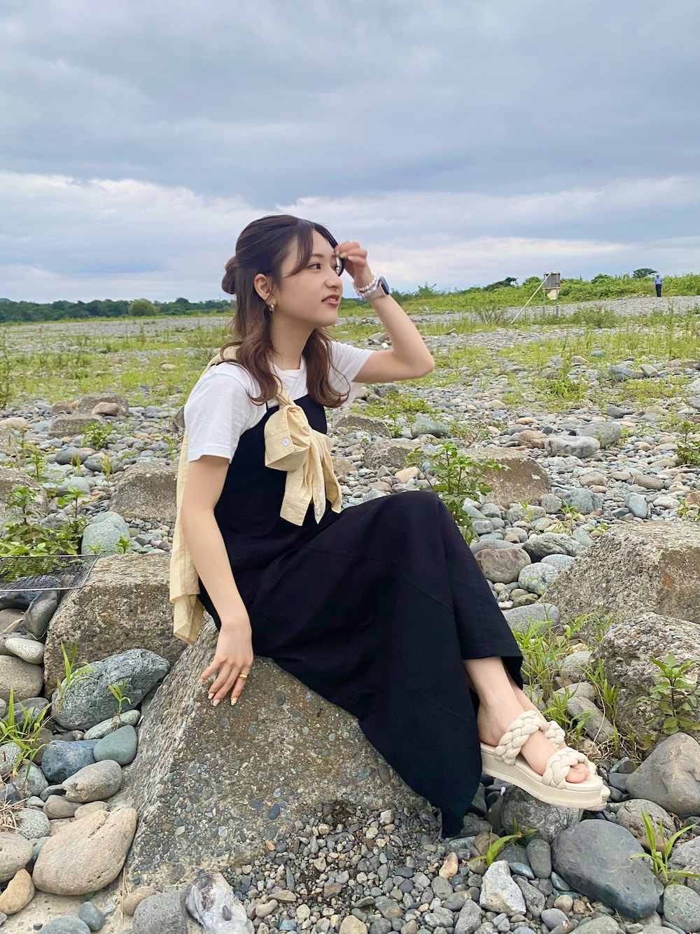 ブラック系のジャンパースカート、イエロー系のシャツ/ブラウス、ホワイト系のサンダルを着用したレディースの秋コーディネートの1枚目の写真