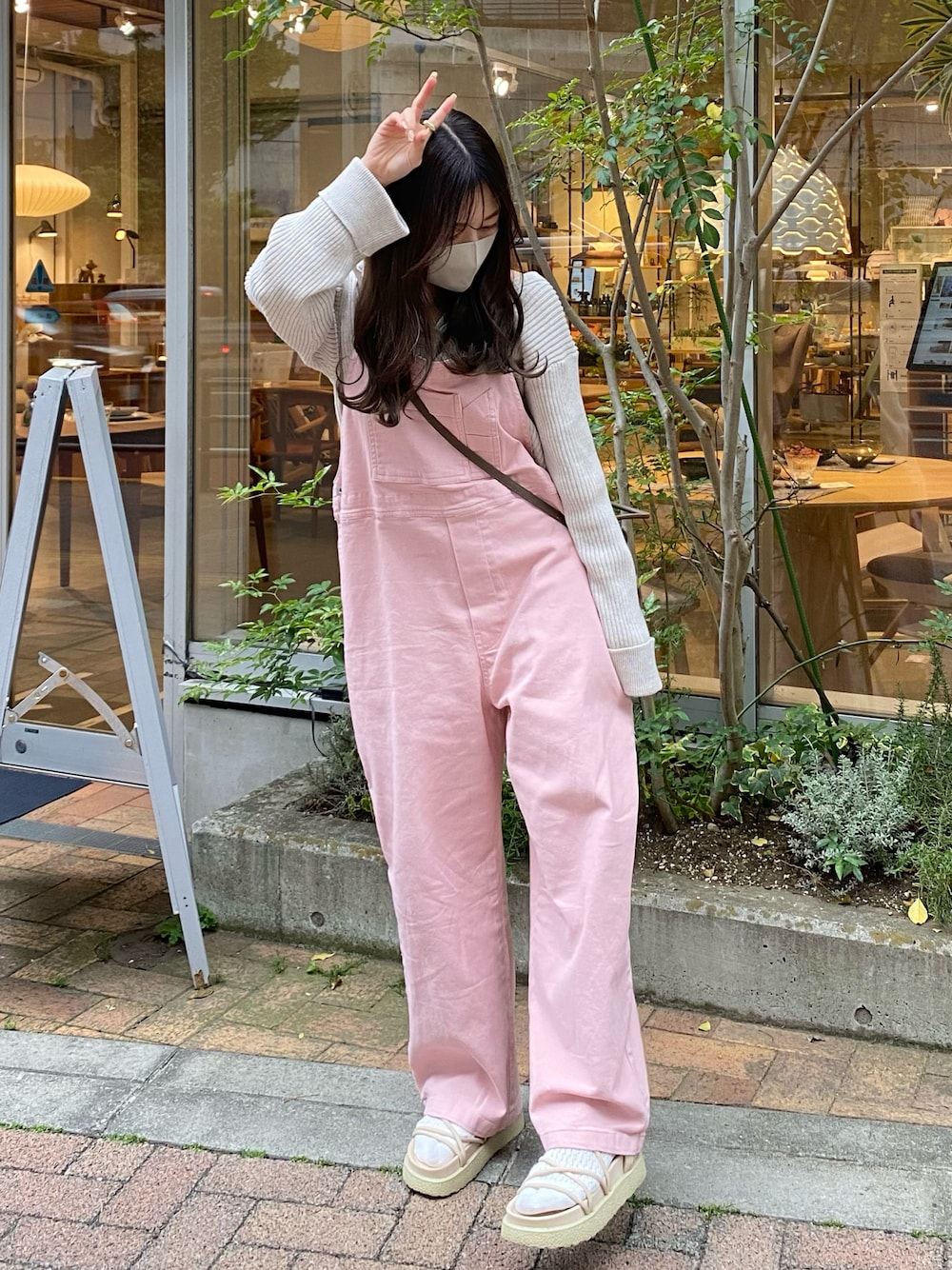 ベージュ系のサンダル、ピンク系のサロペット/オーバーオール、ホワイト系のカーディガン/ボレロを着用したレディースの春コーディネートの1枚目の写真