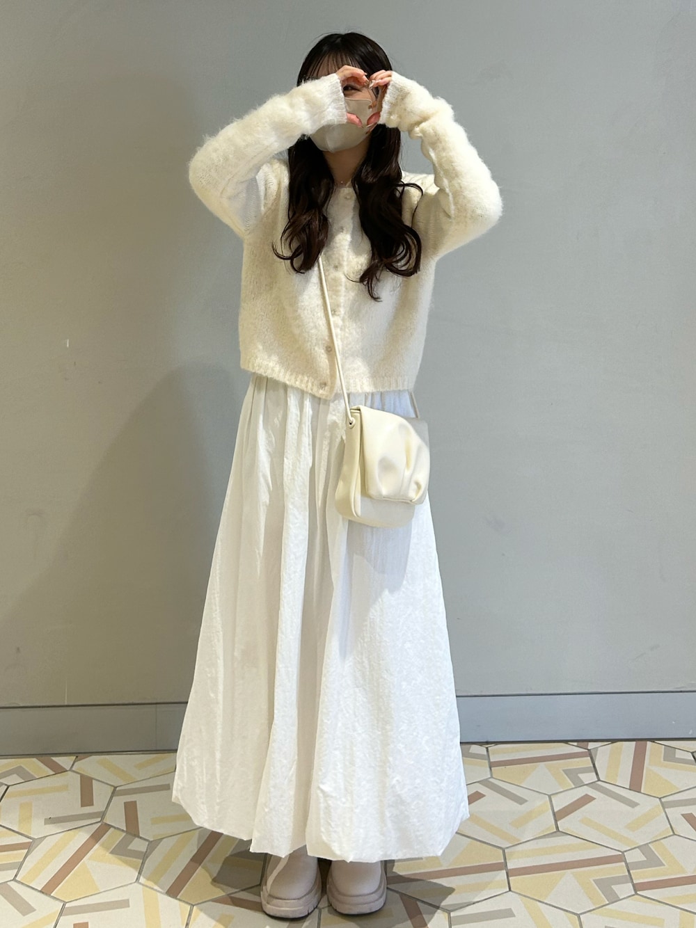 ホワイト系のカーディガン/ボレロ、ホワイト系のショルダーバッグ、ホワイト系のスカートを着用したレディースの冬コーディネートの1枚目の写真