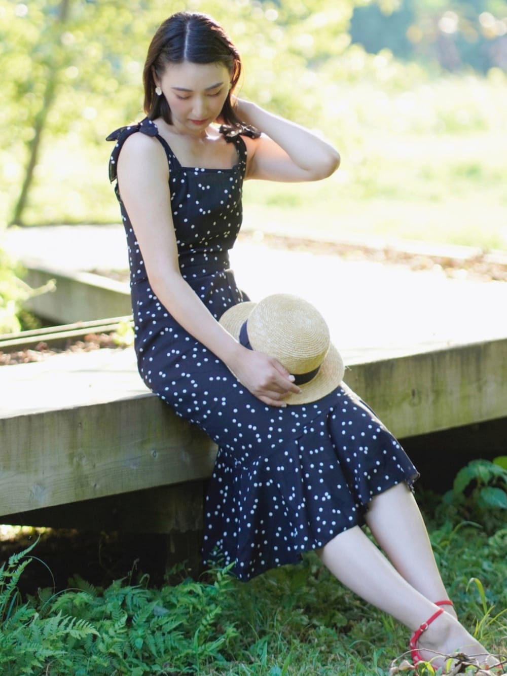 ブラック系のワンピース、レッド系のサンダル、ベージュ系のハットを着用したレディースの夏コーディネートの1枚目の写真