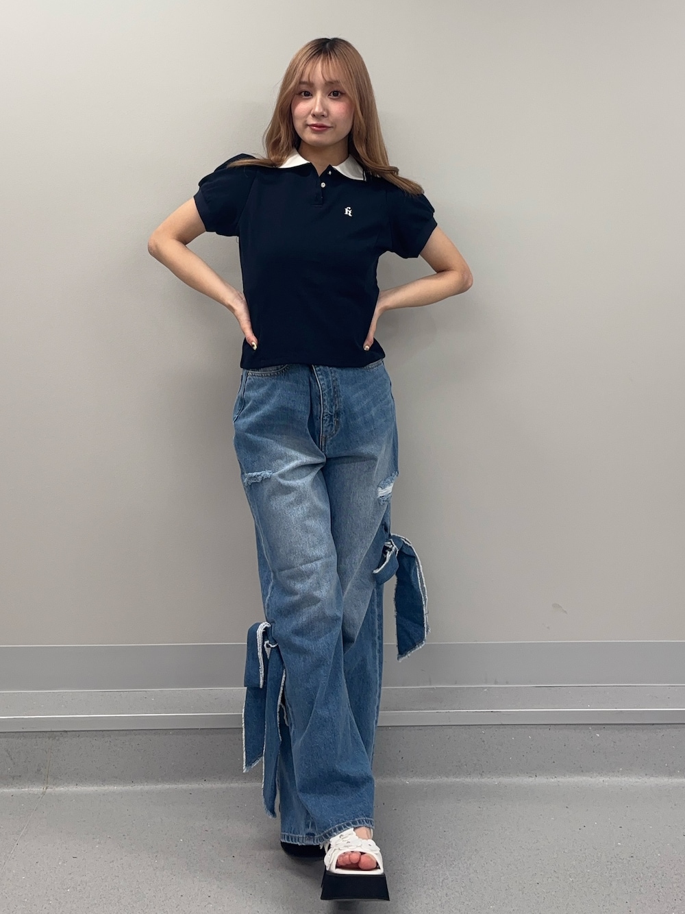 ブルー系のデニムパンツ、ブルー系のポロシャツ、ホワイト系のサンダルを着用したレディースの春コーディネートの1枚目の写真