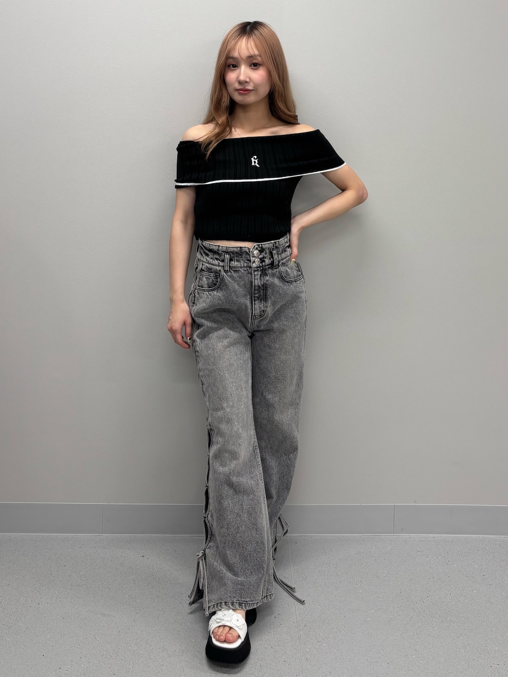 ブルー系のデニムパンツ、ブラック系のニット/セーター、ホワイト系のサンダルを着用したレディースの春コーディネートの1枚目の写真