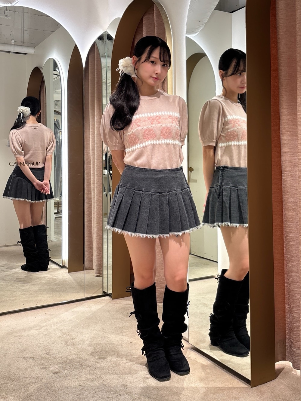 ブラック系のスカート、ピンク系のニット/セーター、ブラック系のブーツを着用したレディースの秋コーディネートの1枚目の写真