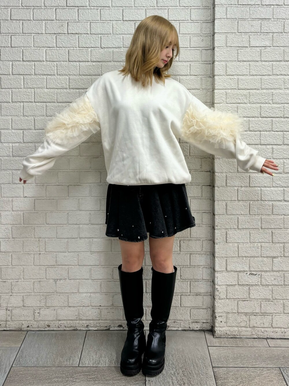 ホワイト系のスウェット、ブラック系のブーツ、ブルー系のスカートを着用したレディースの秋コーディネートの1枚目の写真