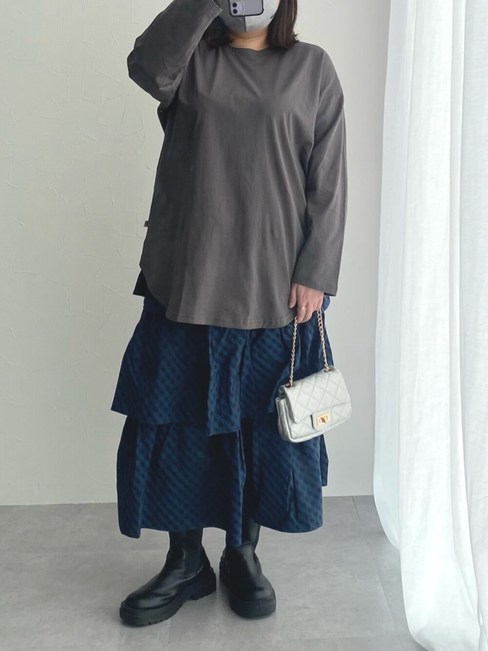 グレー系のチュニック、ブルー系のスカートを着用したレディースの冬コーディネートの1枚目の写真
