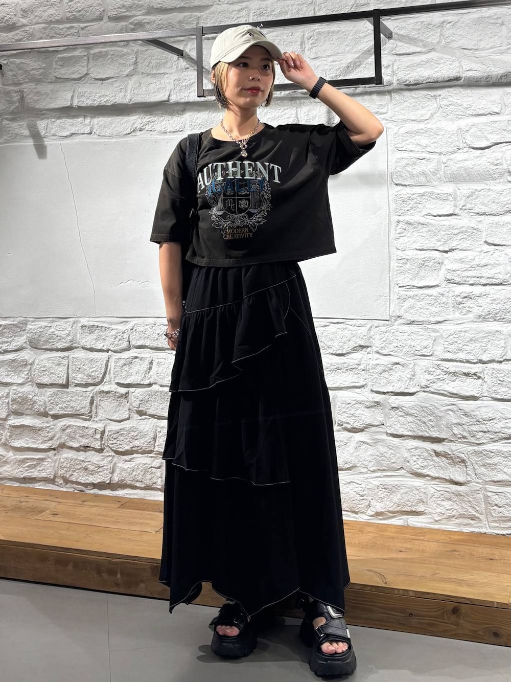 ブラック系のスカート、グレー系のTシャツ/カットソー、ブラック系のショルダーバッグを着用したレディースの夏コーディネートの1枚目の写真