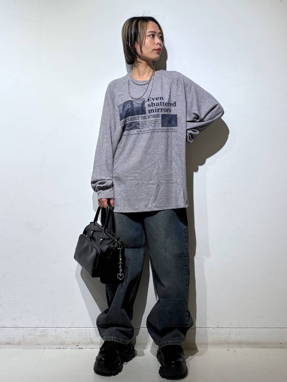 ブラック系のスニーカー、ブルー系のデニムパンツ、ブラック系のショルダーバッグを着用したレディースの春コーディネートの1枚目の写真