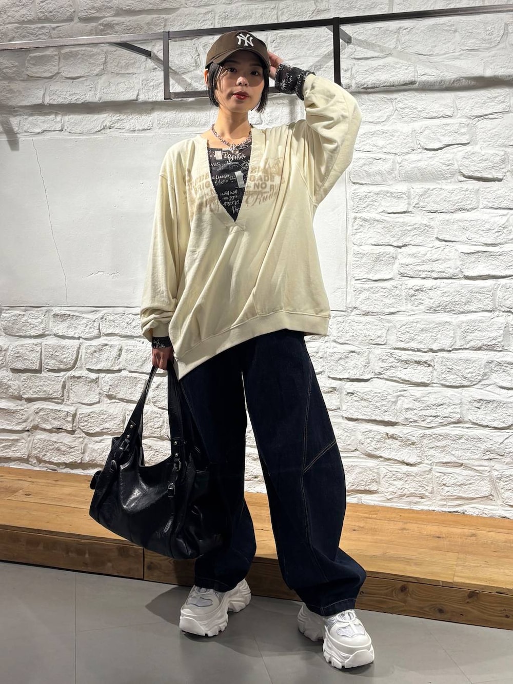 ブルー系のデニムパンツ、ホワイト系のスニーカー、ブラック系のトートバッグを着用したレディースの秋コーディネートの1枚目の写真