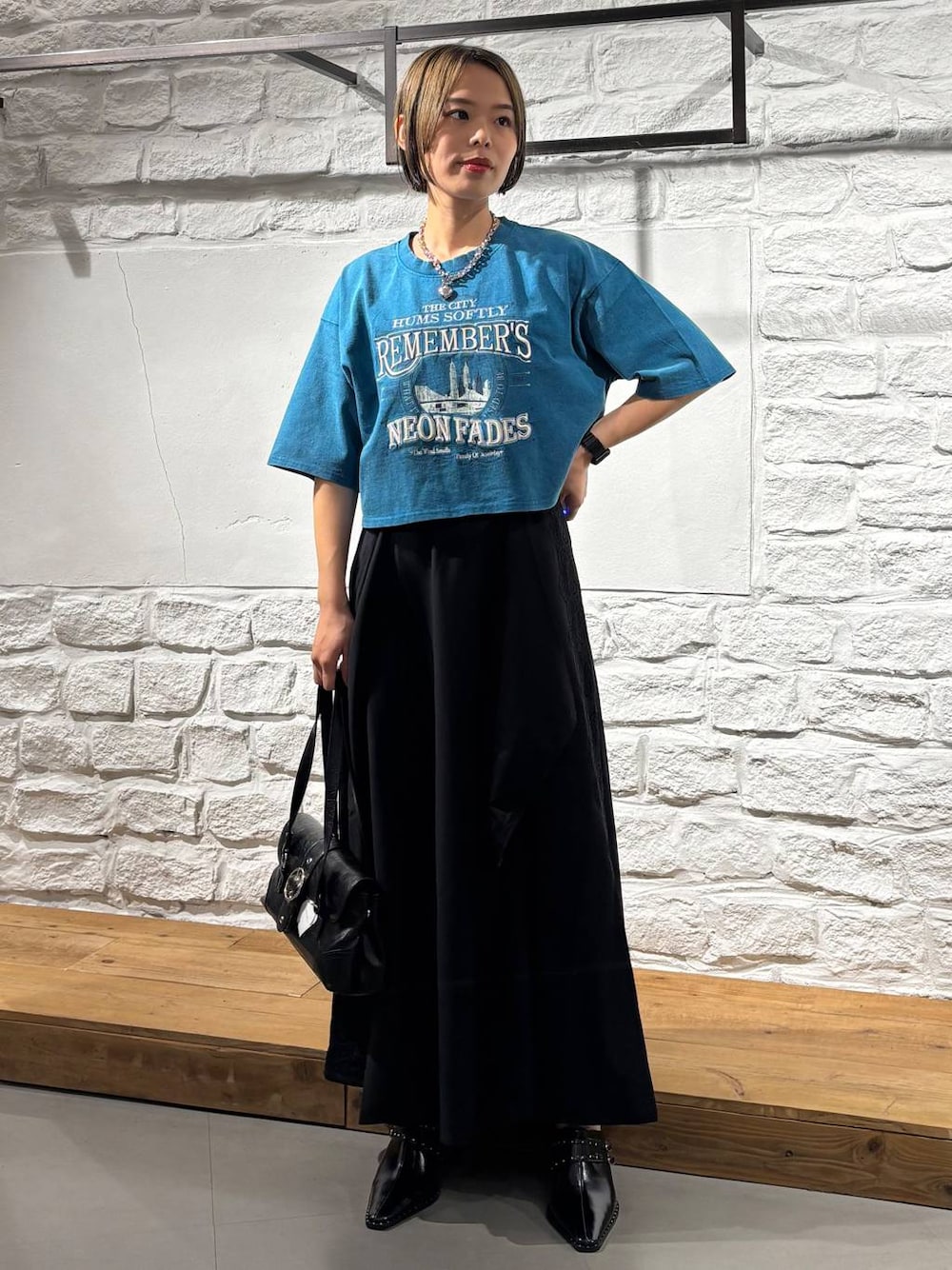 ブラック系のスカート、ブルー系のTシャツ/カットソー、ブラック系のショルダーバッグを着用したレディースの夏コーディネートの1枚目の写真
