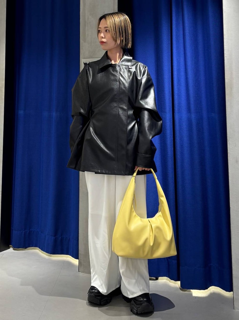 ブラック系のスニーカー、イエロー系のトートバッグ、ホワイト系のスラックスを着用したレディースの春コーディネートの1枚目の写真