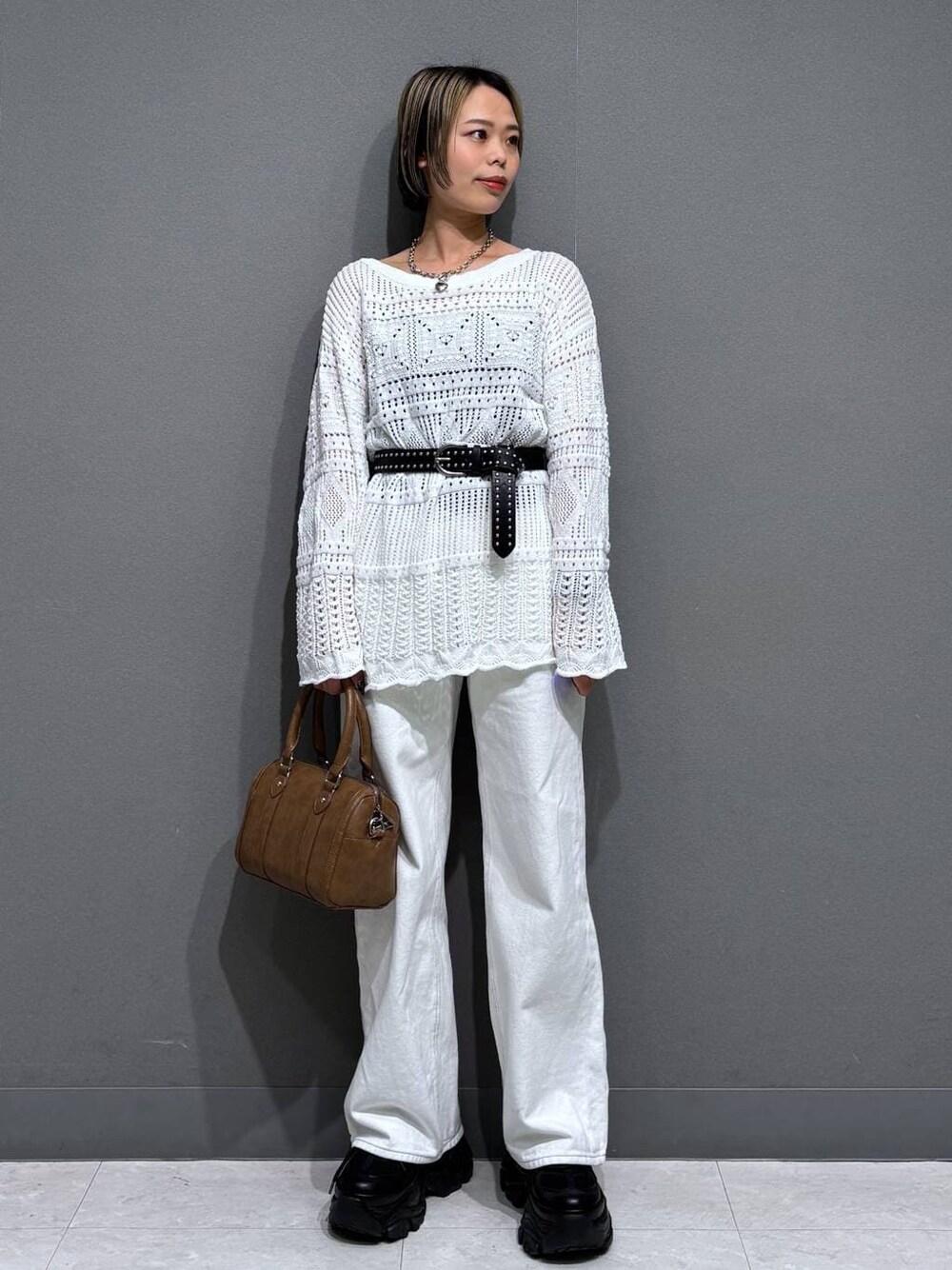 ブラック系のスニーカー、ホワイト系のスラックス、ブラウン系のボストンバッグを着用したレディースの春コーディネートの1枚目の写真