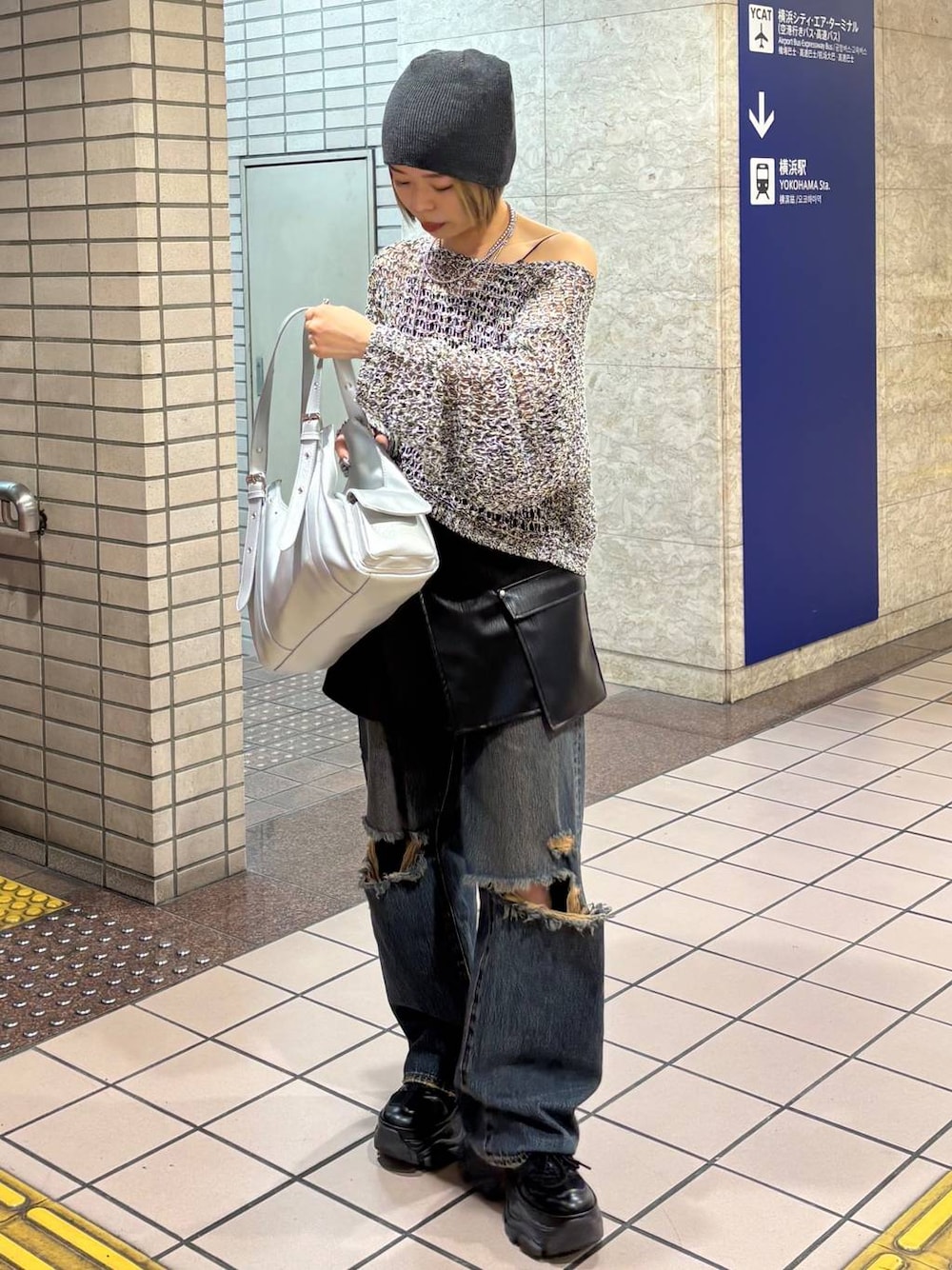 ブラック系のスニーカー、ブラック系のニット/セーター、シルバー系のハンドバッグを着用したレディースの春コーディネートの1枚目の写真