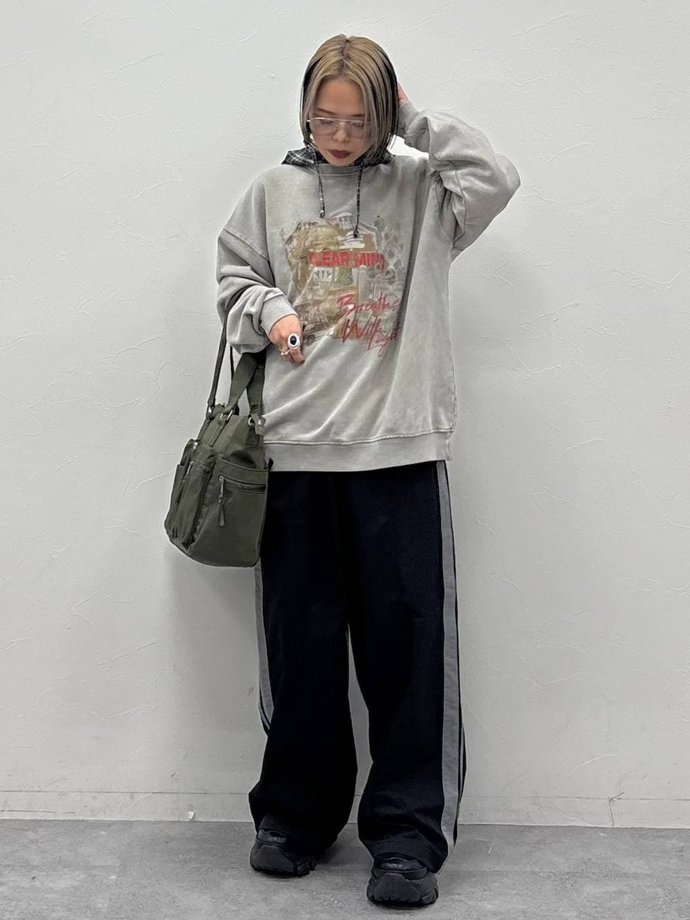 ブラック系のスニーカー、グリーン系のボストンバッグ、ブラック系のスウェットパンツを着用したレディースの冬コーディネートの1枚目の写真